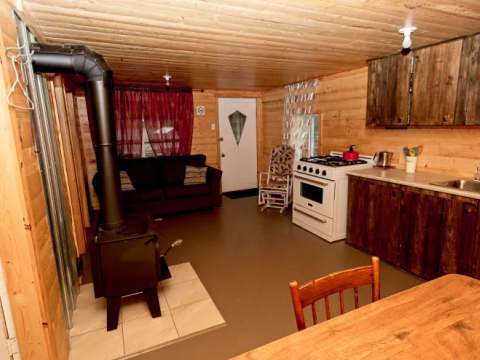Vue d'ensemble de l'aire de vie principale comprenant la cuisine, le salon et le poêle à bois.