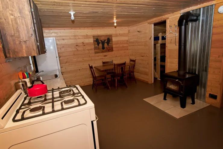 La cuisine et la salle à manger du chalet incluent un poêle à bois et une cuisinière au gaz.