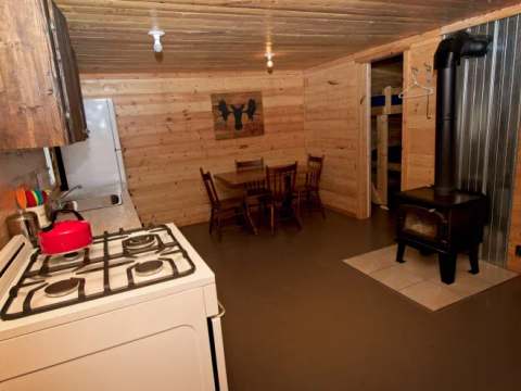 La cuisine et la salle à manger du chalet incluent un poêle à bois et une cuisinière au gaz.