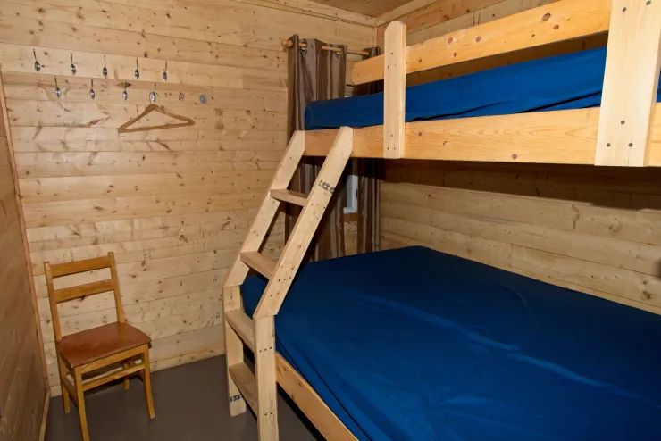 Cette chambre est équipée de lits superposés en bois et d'une chaise.