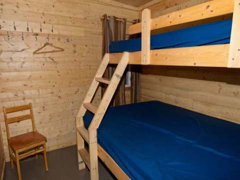 Cette chambre est équipée de lits superposés en bois et d'une chaise.