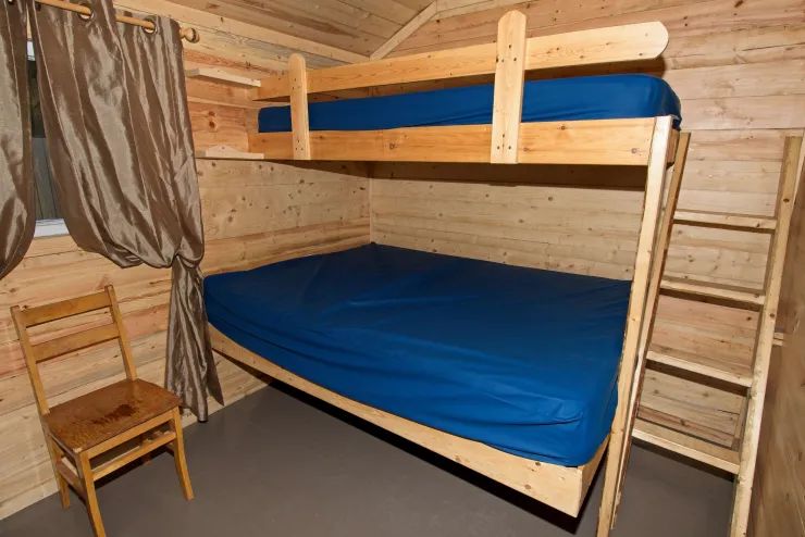 Cette chambre de chalet comprend un lit superposé avec une structure en bois.