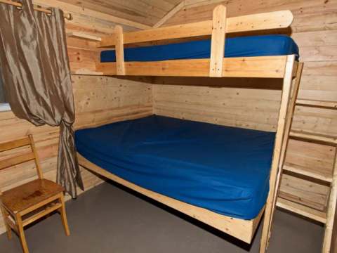 Cette chambre de chalet comprend un lit superposé avec une structure en bois.