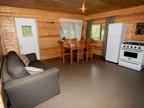L'espace de vie du chalet comprend un coin salon, une table à manger et une cuisine équipée.