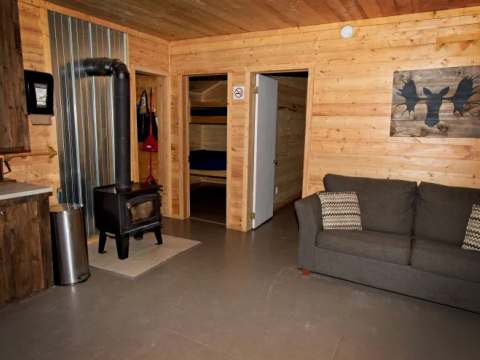 Le salon du chalet comprend un poêle à bois, un canapé et un accès aux chambres à coucher.