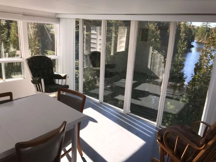 La véranda vitrée du chalet offre un espace repas lumineux avec vue sur la nature environnante.