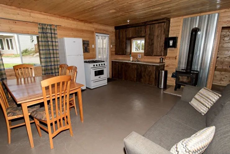 L'aire ouverte du chalet comprend une cuisine équipée, un coin repas et un salon avec poêle à bois.
