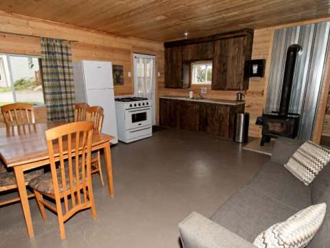 L'aire ouverte du chalet comprend une cuisine équipée, un coin repas et un salon avec poêle à bois.