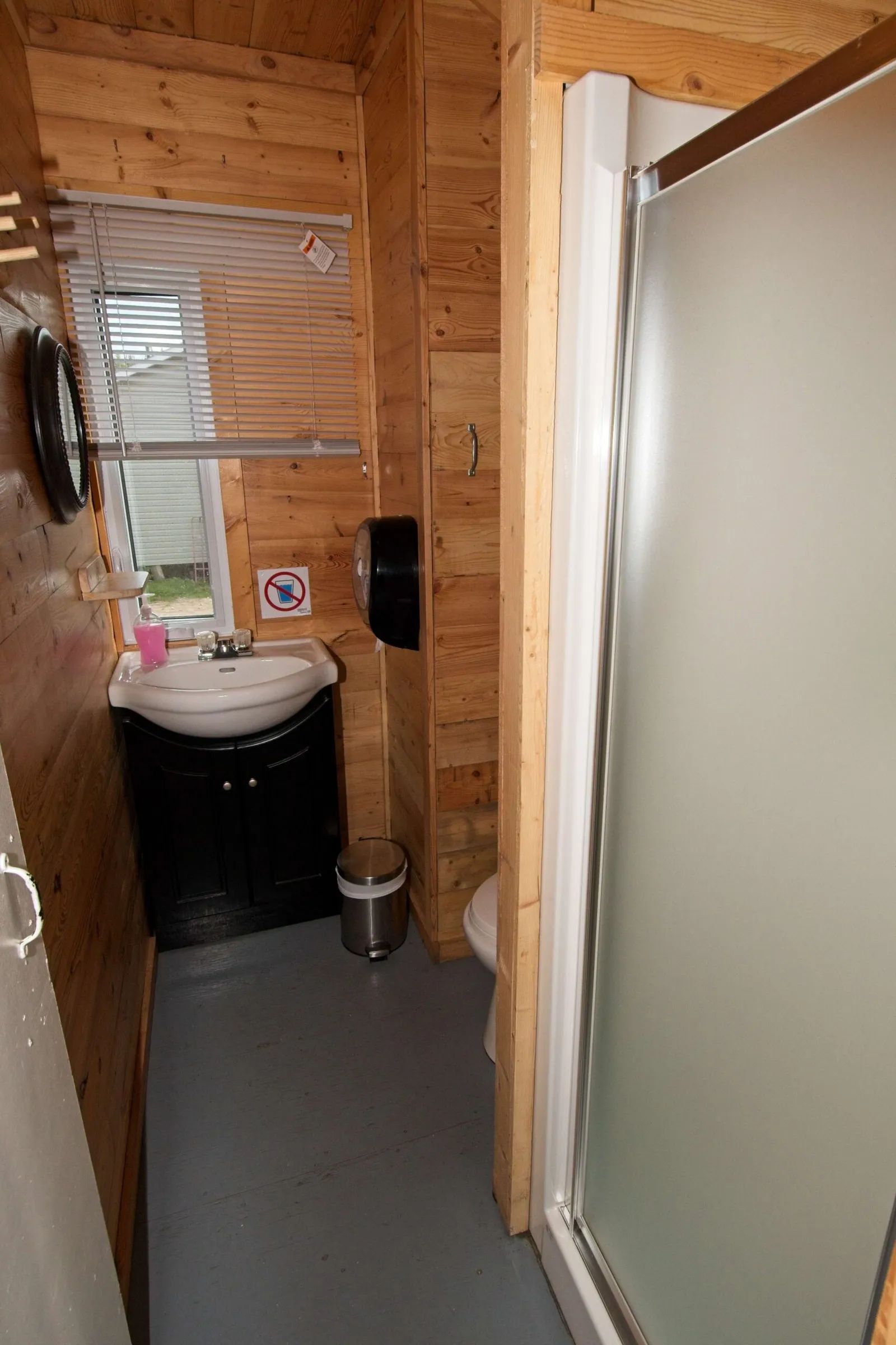 Cette salle de bain de chalet comprend une douche, une toilette et un lavabo.