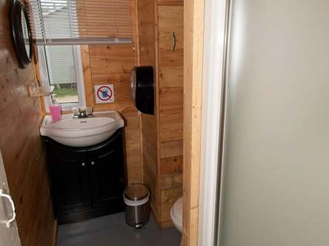 Cette salle de bain de chalet comprend une douche, une toilette et un lavabo.