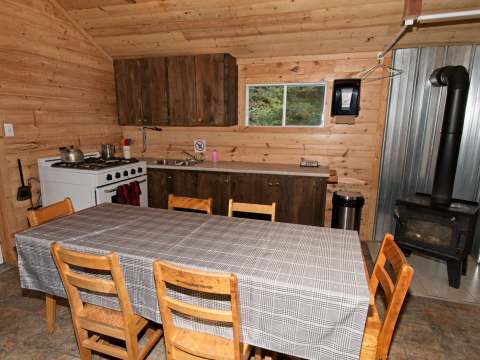 La cuisine équipée du chalet dispose d'une table à manger et d'un poêle à bois.