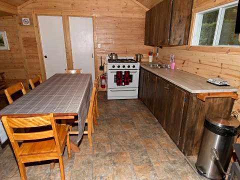 La cuisine équipée et l'espace repas du chalet 4 disposent d'une cuisinière et d'une table en bois.