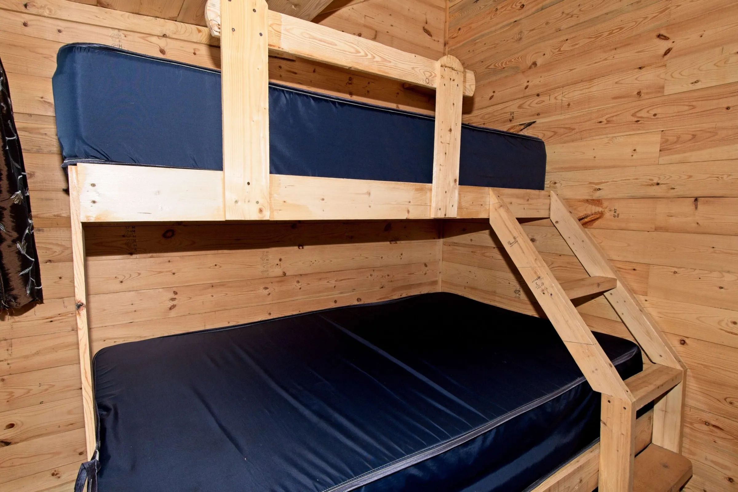 Cette chambre du chalet comprend un lit superposé avec des matelas sombres.