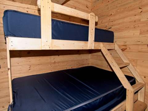 Cette chambre du chalet comprend un lit superposé avec des matelas sombres.