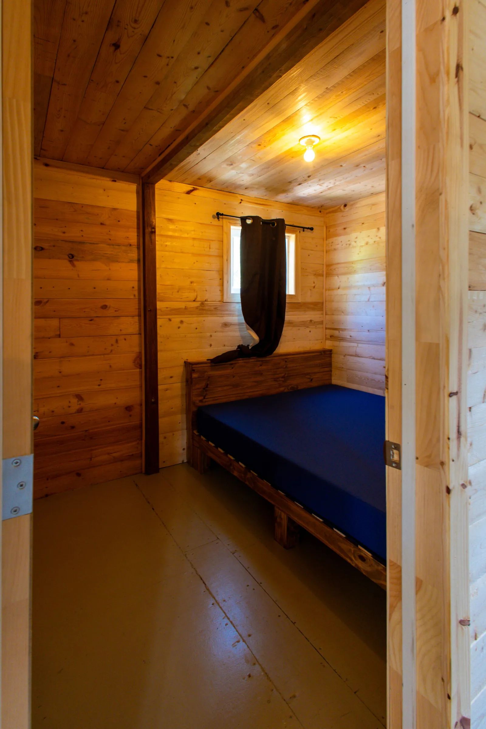 Vue sur une chambre à coucher avec murs en bois et lit simple dans le chalet 5.