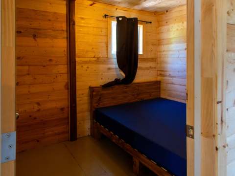 Vue sur une chambre à coucher avec murs en bois et lit simple dans le chalet 5.