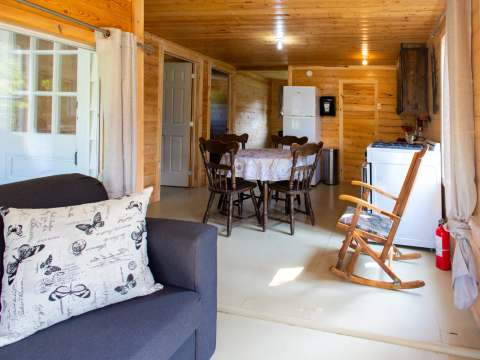 Espace de vie ouvert comprenant un salon, une table de salle à manger et une cuisine équipée.