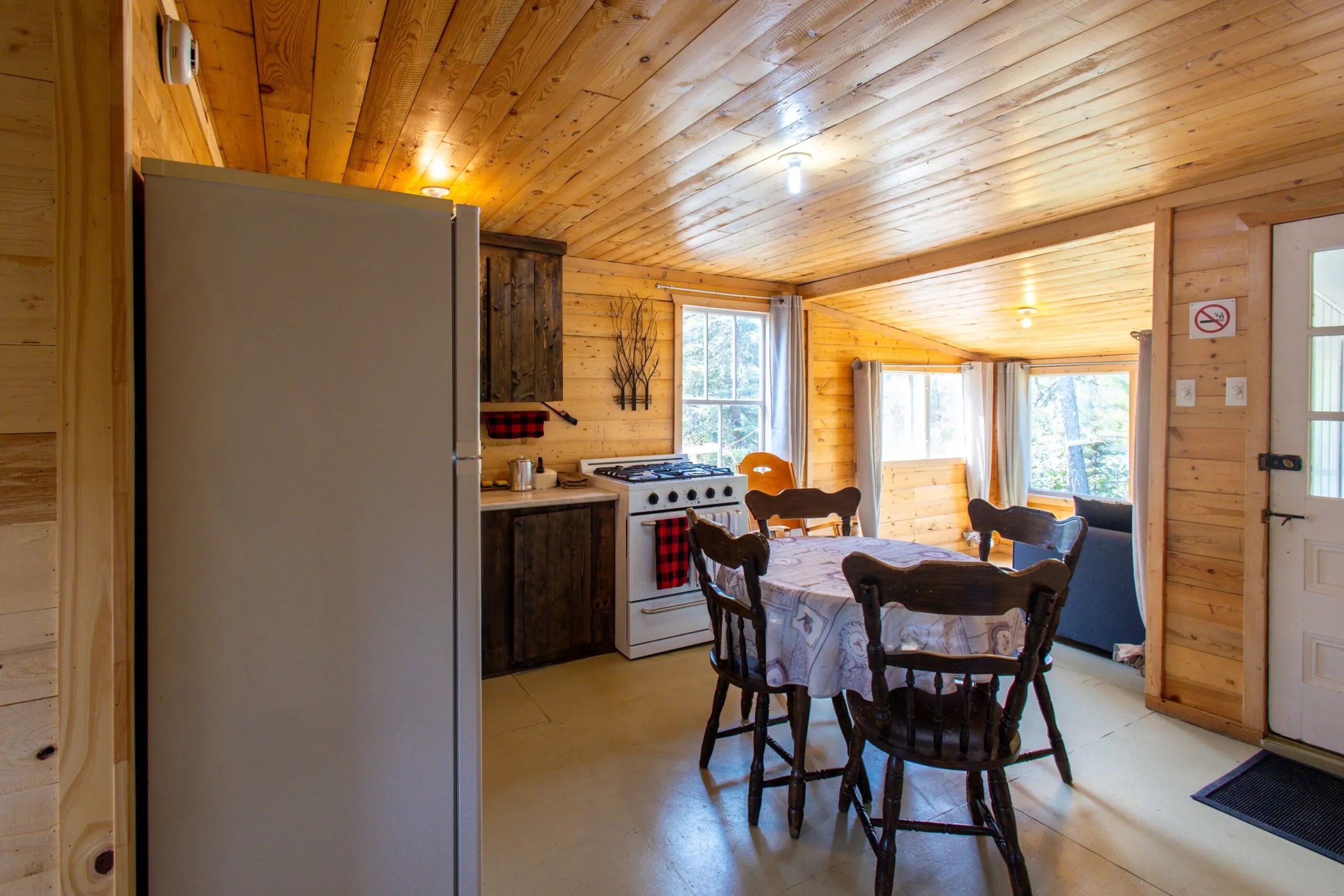 La cuisine du chalet comprend une table à manger, une cuisinière et un réfrigérateur.