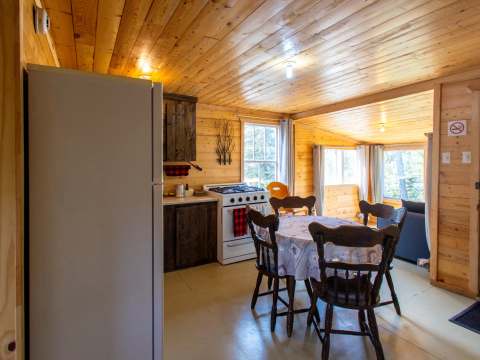 La cuisine du chalet comprend une table à manger, une cuisinière et un réfrigérateur.