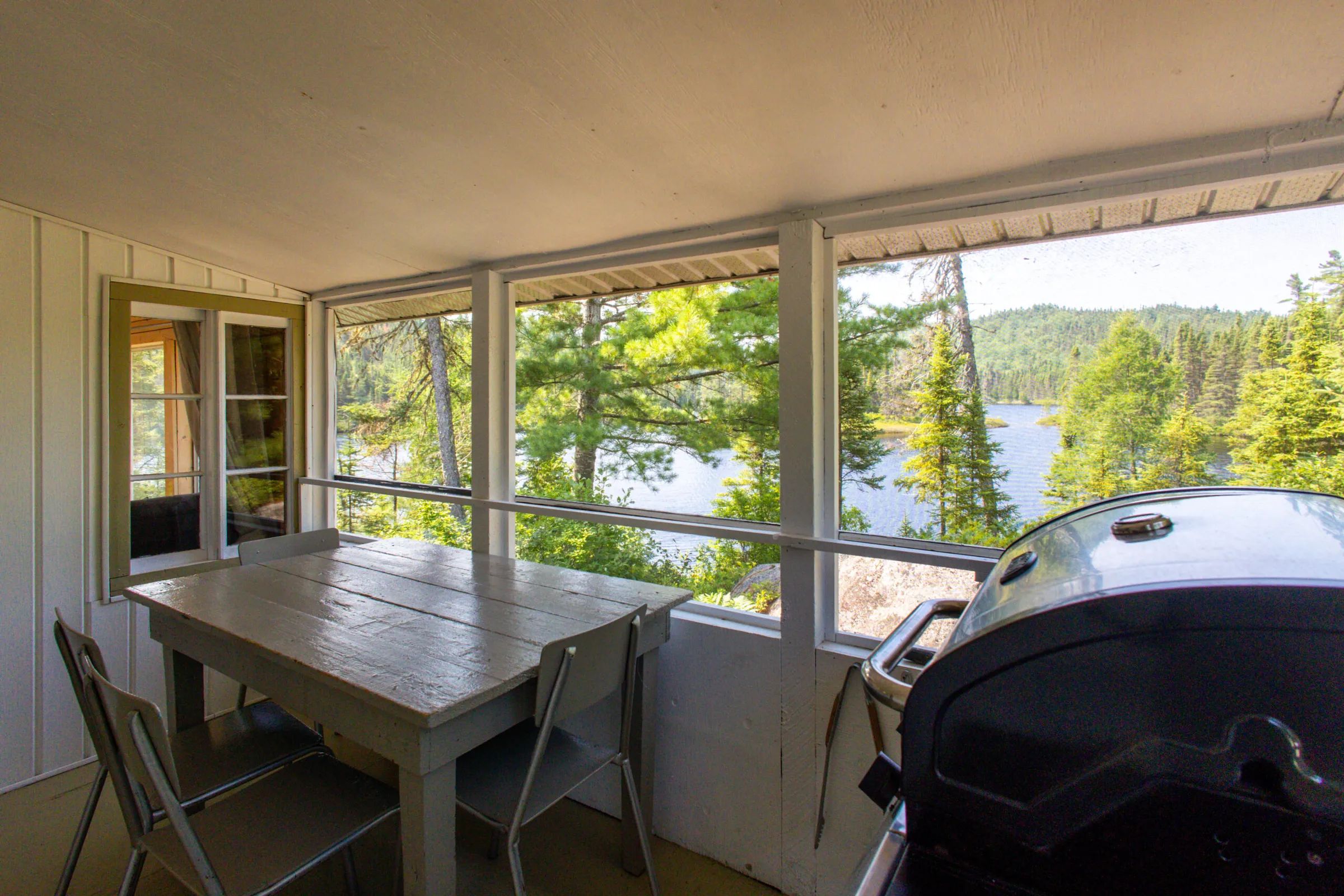La véranda du chalet 5 offre une vue sur le lac et inclut une table à manger ainsi qu'un barbecue.
