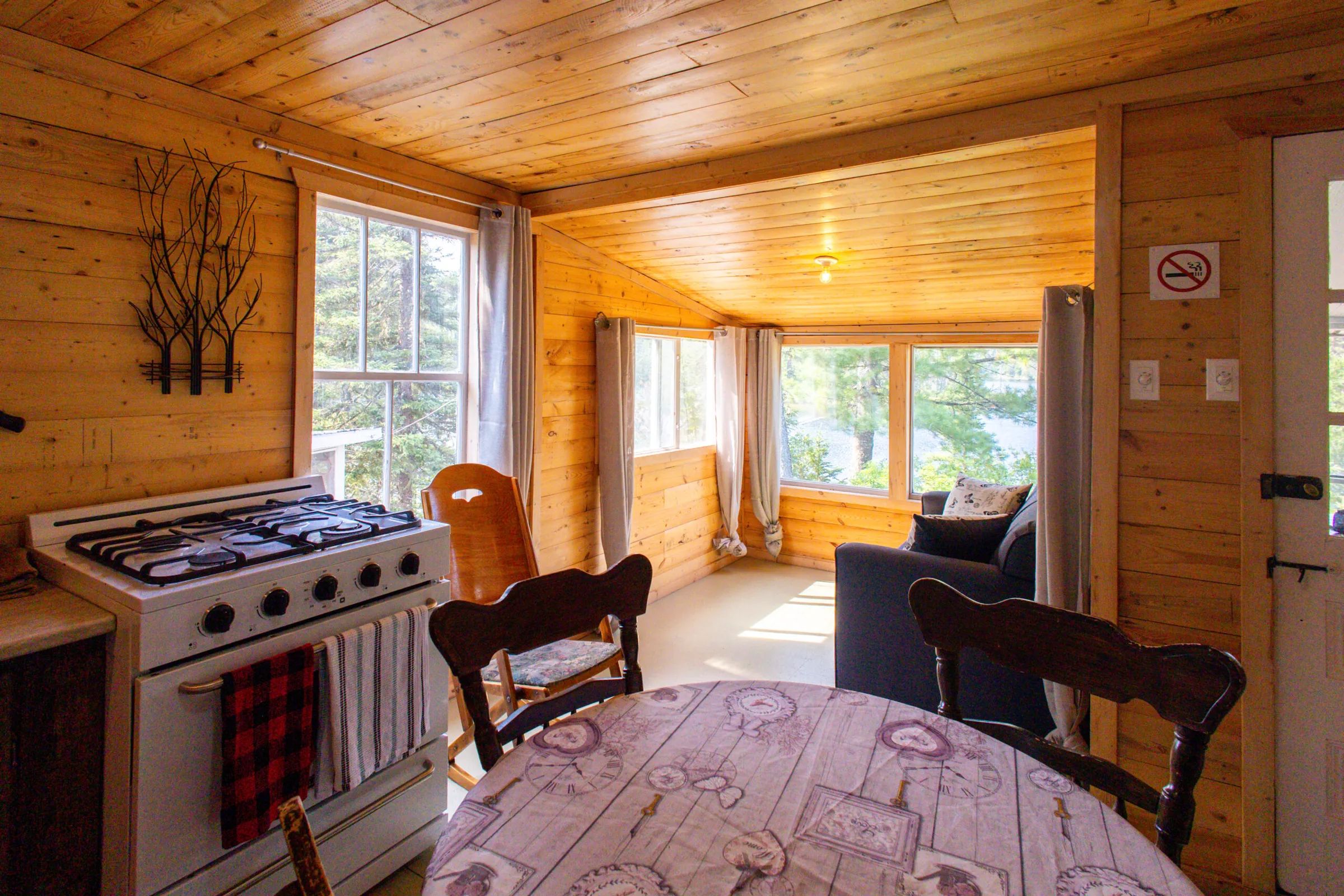 Vue sur la cuisine et l'espace de vie du chalet 5 avec ses murs en bois naturel.