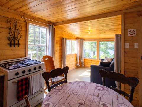 Vue sur la cuisine et l'espace de vie du chalet 5 avec ses murs en bois naturel.