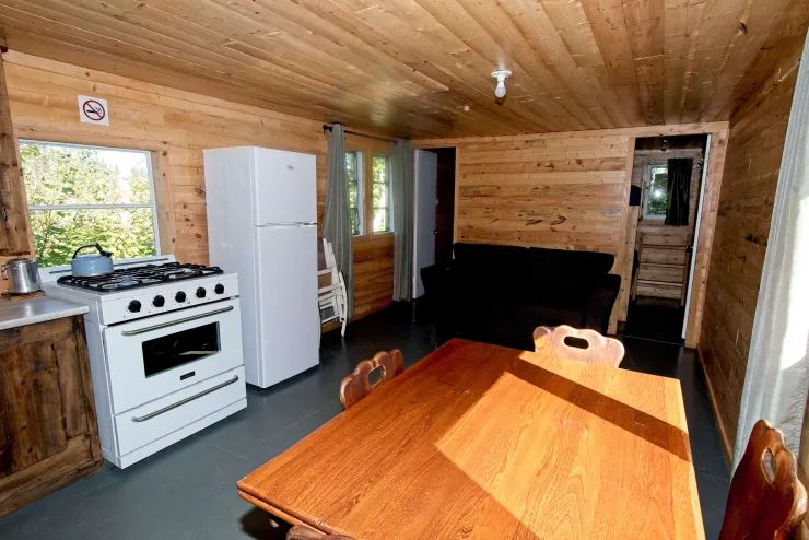 L'aire ouverte du chalet comprend une cuisine équipée, une table à manger et un salon.