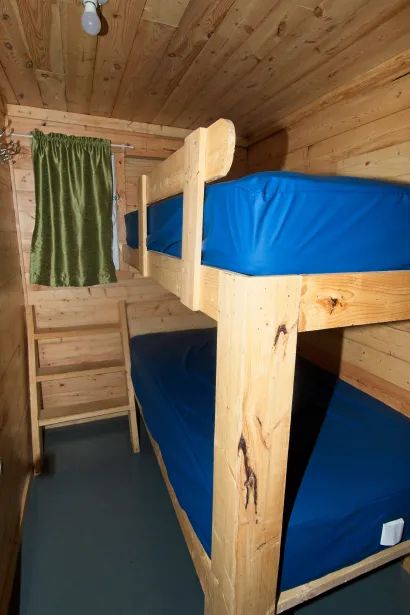 Un lit superposé en bois est installé dans une chambre chaleureuse aux murs lambrissés.