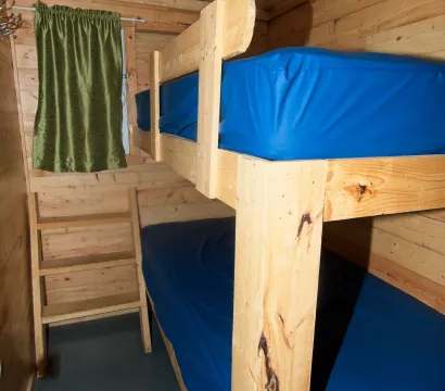 Un lit superposé en bois est installé dans une chambre chaleureuse aux murs lambrissés.