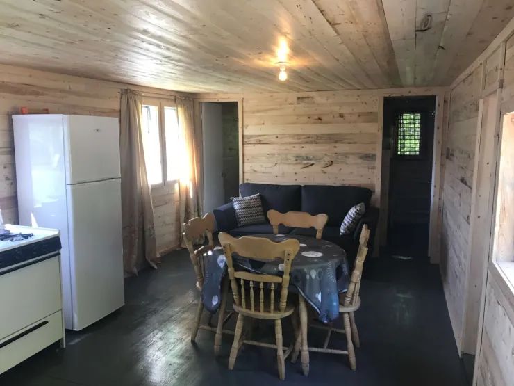 L'aire de vie du chalet comprend une table à manger, un coin salon et une cuisine équipée.