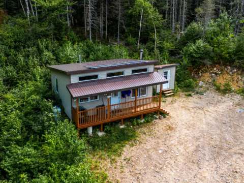 Vue aérienne du chalet 7 situé en forêt avec sa terrasse couverte et ses panneaux solaires.