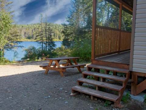 Vue sur le lac depuis la terrasse du chalet avec une table de pique-nique à proximité.