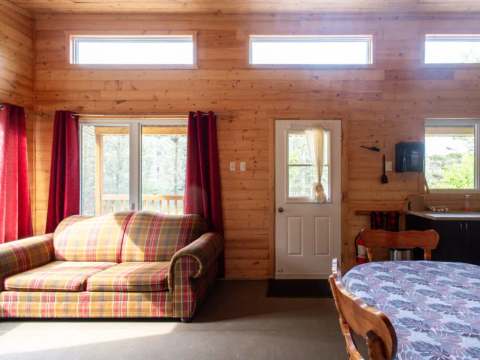 L'aire ouverte du chalet comprend un coin salon avec divan et une salle à manger adjacente.
