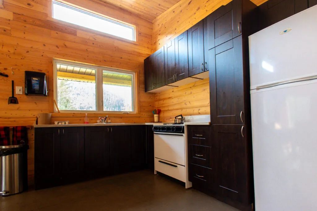 La cuisine équipée du chalet dispose d'armoires en bois sombre et d'une cuisinière fonctionnelle.