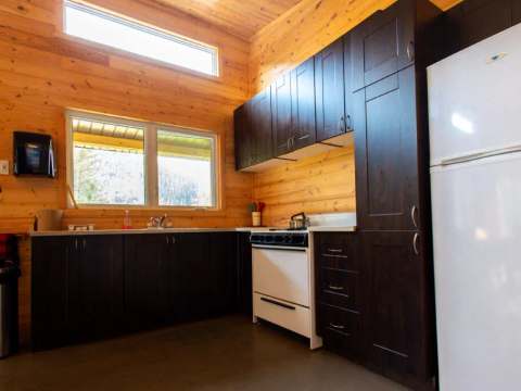 La cuisine équipée du chalet dispose d'armoires en bois sombre et d'une cuisinière fonctionnelle.