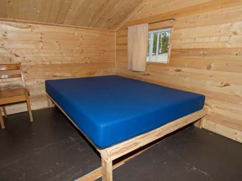 Cette chambre rustique est équipée d'un lit simple et d'une chaise en bois.