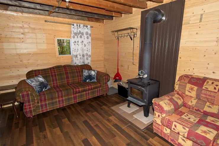 Le salon du chalet comprend deux sofas confortables et un poêle à bois pour vos soirées de détente.