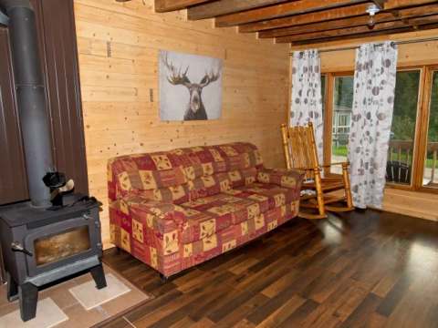 Le salon du chalet 3 comprend un foyer au bois, un canapé confortable et une chaise berçante.