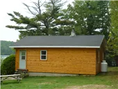 Side view of cabin 1A surrounded by trees and equipped with a picnic table.
