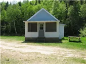 Exterior view of cottage 1A located near the forest with a picnic table nearby.
