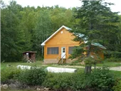 Exterior view of cottage 1A located in the forest near the shoreline.