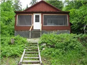 Front view of the cabin featuring its access stairs and screened veranda.