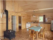 The cabin interior includes a kitchen area, a dining table, and a wood stove.