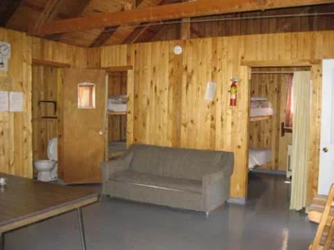 View of the open-plan living area with a sofa, dining table, and access to the bedrooms.