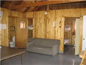 The cottage's common area features a sofa, a table and access to sleeping quarters.
