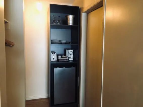 A storage unit including a small refrigerator and a coffee maker in an inn room.