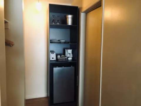 A storage unit including a small refrigerator and a coffee maker in an inn room.