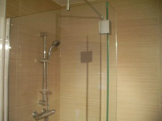 This modern shower with a glass panel is part of our inn's bathroom.