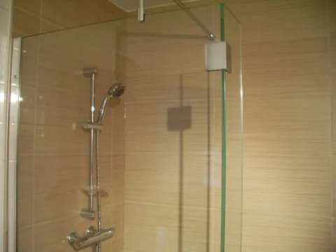 This modern shower with a glass panel is part of our inn's bathroom.