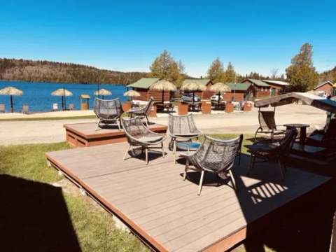 Outdoor relaxation area furnished with chairs facing the lake and the outfitter's cabins.
